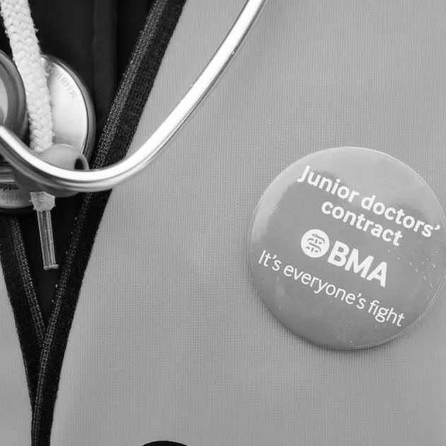 A demonstrator wears a BMA (British Medical Association) badge alongside her stethoscope