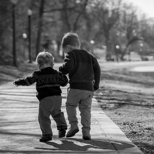 Two children walking by a pond