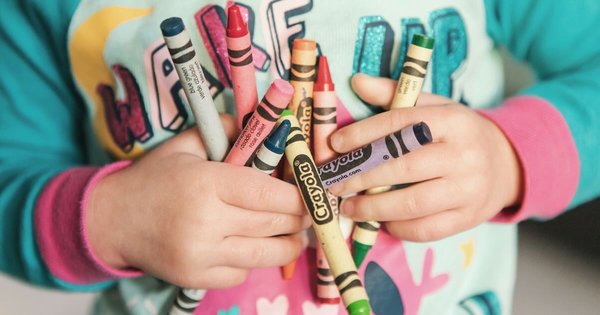 A toddler clutching crayons to their chest
