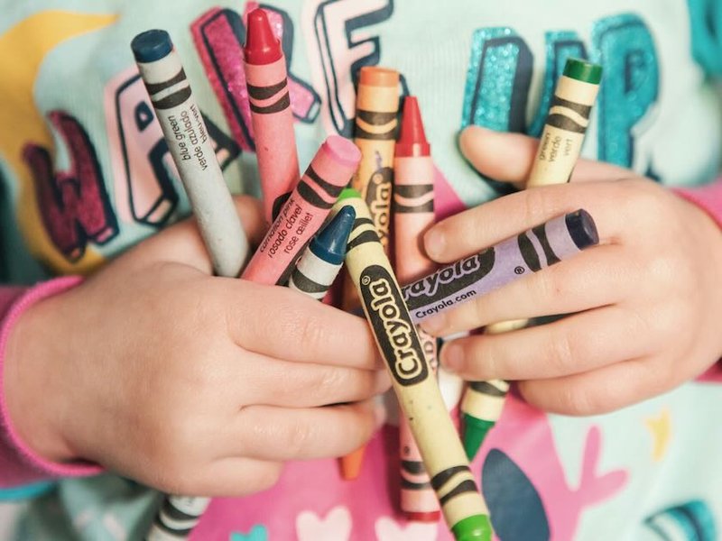 A toddler clutching crayons to their chest