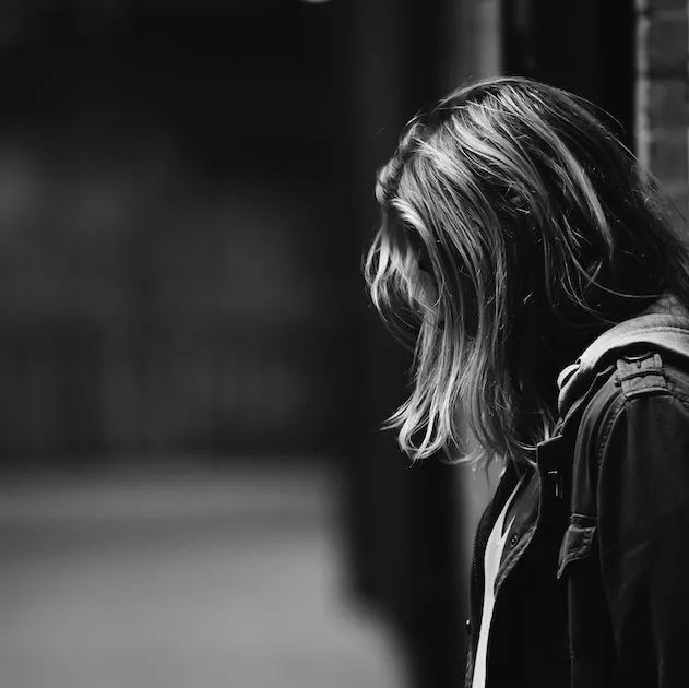 A girl stands in a gloomy hallway