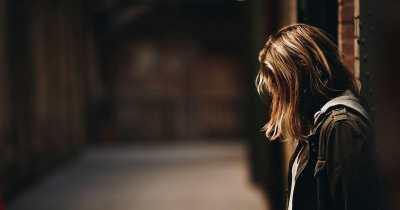 A girl stands in a gloomy hallway