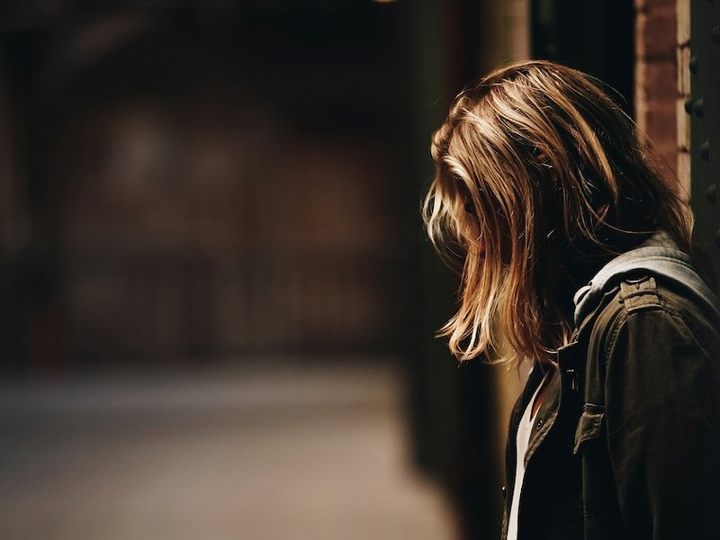 A girl stands in a gloomy hallway
