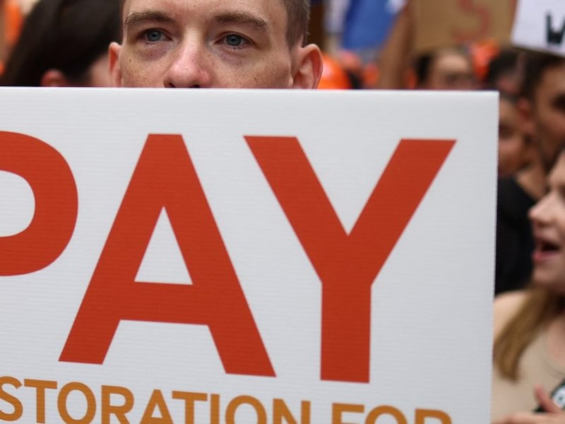 A demonstrator holds a placard during a protest calling for better pay for Junior Doctors in Whitehall, outside the gates of Downing Street in central London on August 11, 2023