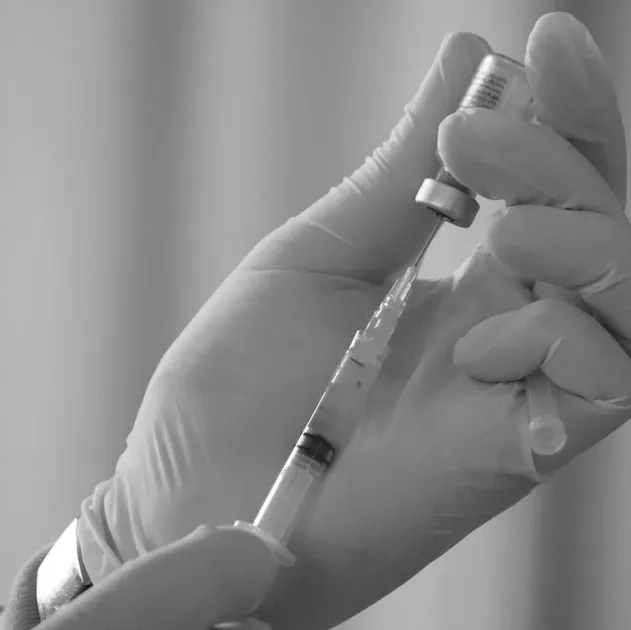 A gloved hand filling a syringe