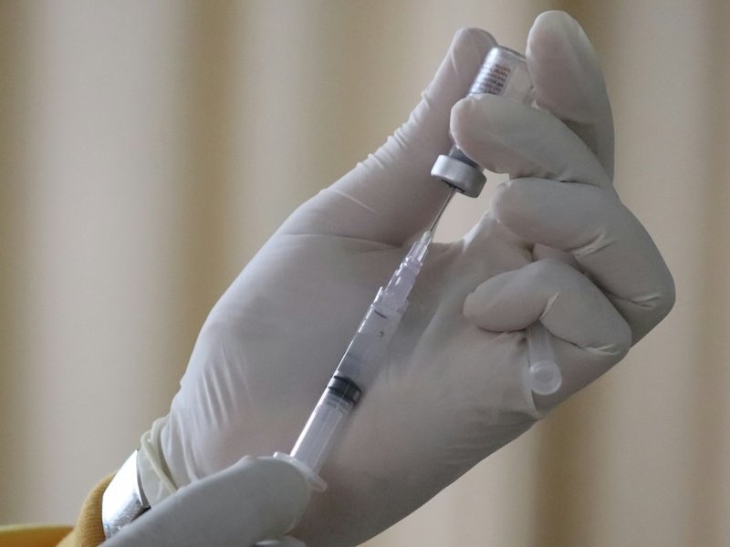 A gloved hand filling a syringe