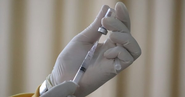 A gloved hand filling a syringe