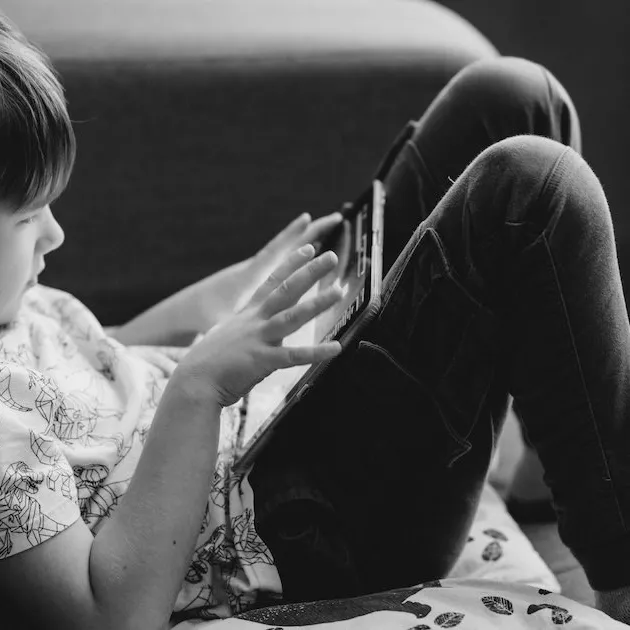 A young child using a tablet on a sofa