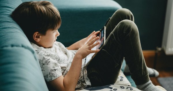A young child using a tablet on a sofa
