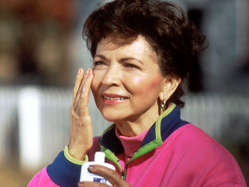 An older woman applying sunscreen to her face