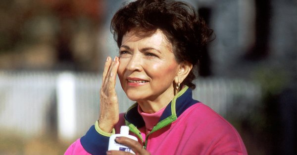 An older woman applying sunscreen to her face