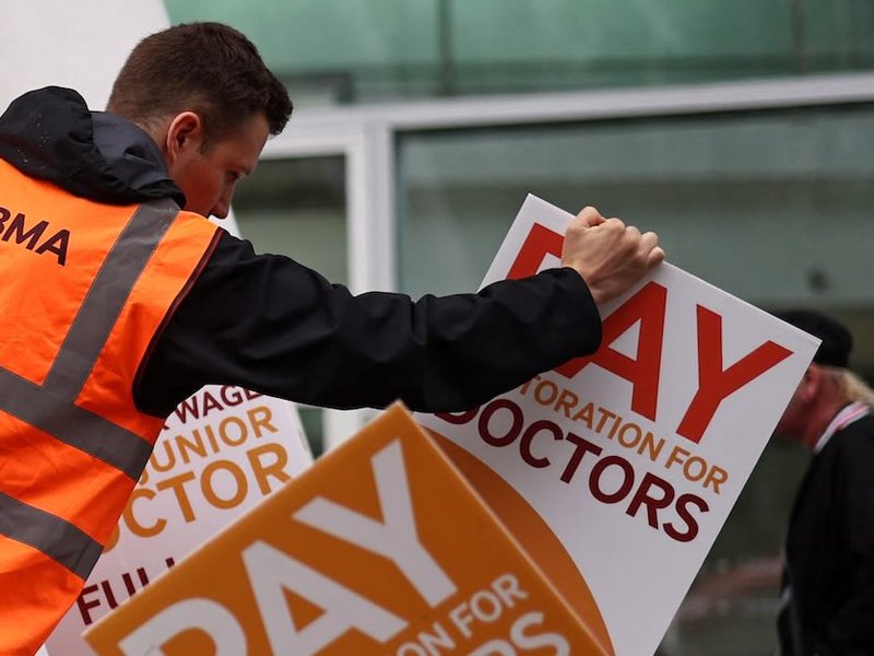An organiser arranges BMA-branded placards calling for better pay outside a hospital in central London in 2023.