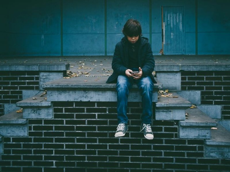 A boy sitting on steps looking at a phone