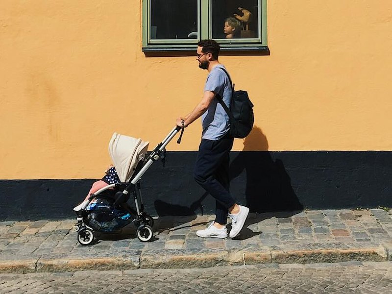 Man walks in a city street with a pushchair