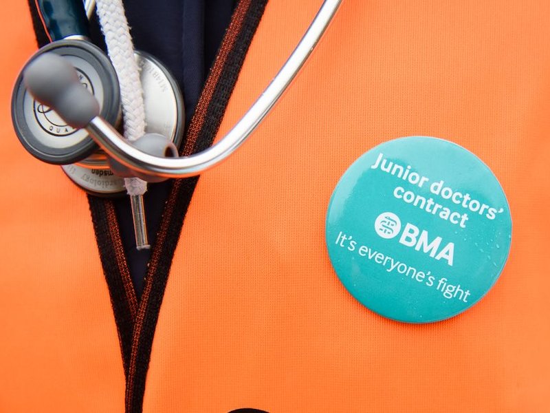 A demonstrator wears a BMA (British Medical Association) badge alongside her stethoscope