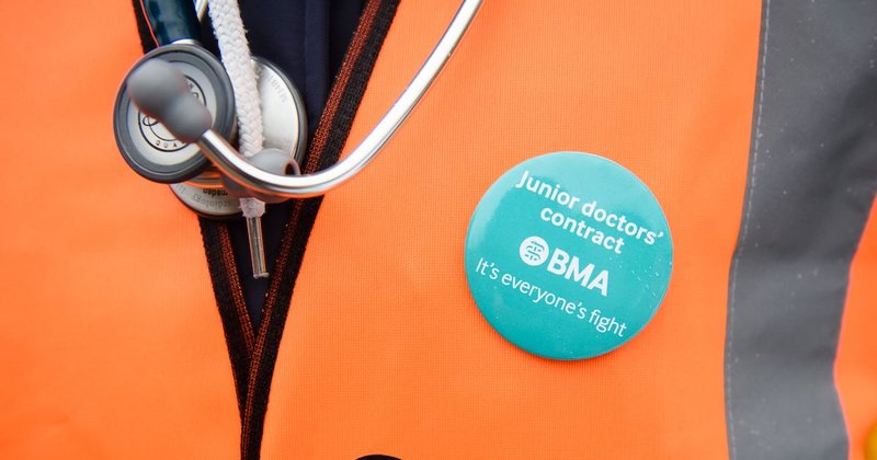 A demonstrator wears a BMA (British Medical Association) badge alongside her stethoscope
