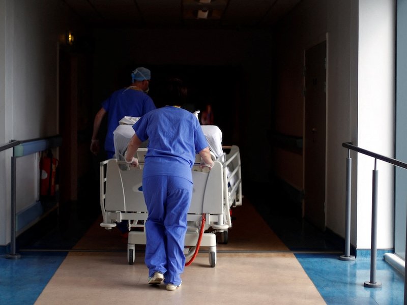 Medical staff pushing a bed through a hospital corridor