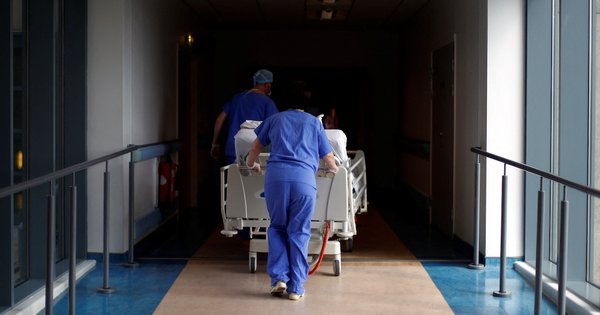 Medical staff pushing a bed through a hospital corridor