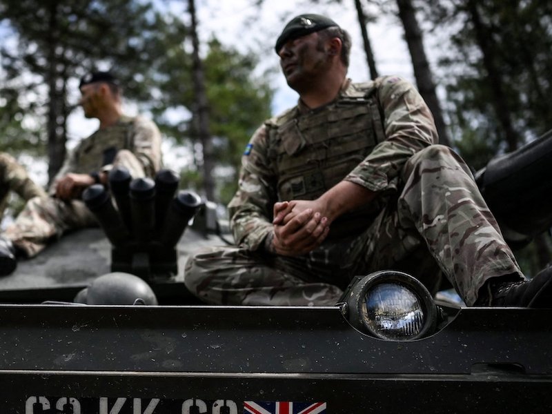 Armed forces personnel sit on a tank during a training session