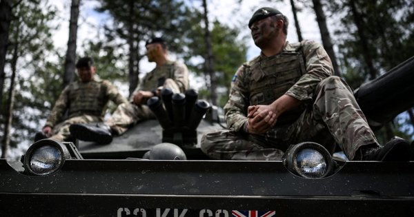 Armed forces personnel sit on a tank during a training session