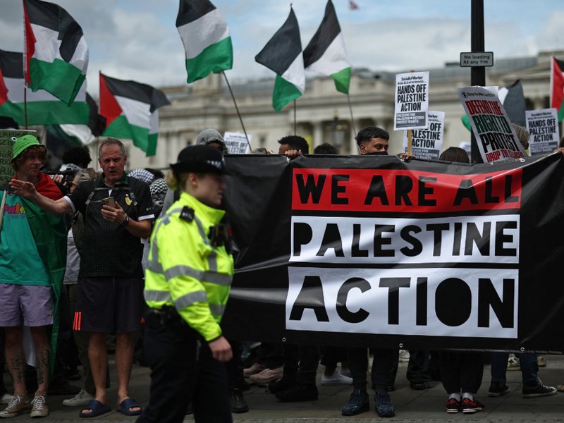 Police officers monitor protesters holding a banner in support of pro-Palestinian group Palestine Action in London this week.