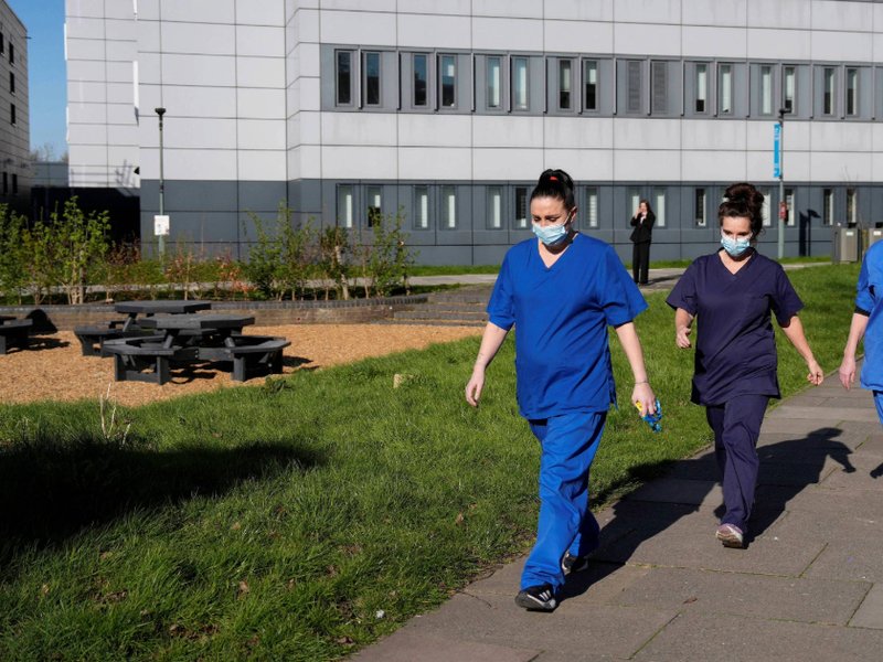 An image of people wearing medical scrubs and face masks walk across campus at the University of Kent in Canterbury, following an outbreak of meningitis.