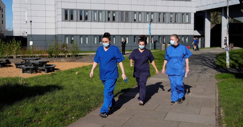 An image of people wearing medical scrubs and face masks walk across campus at the University of Kent in Canterbury, following an outbreak of meningitis.