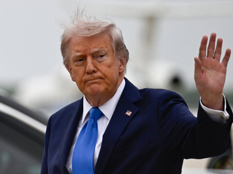 US President Donald Trump waves after stepping off Air Force One at Joint Base Andrews upon returning from Florida on 25 April 2026.
