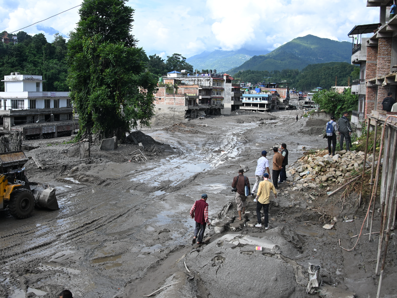 Workers use excavators to clear the mud following flash floods in Trishuli in Nepal's Nuwakot district on August 27, 2026.