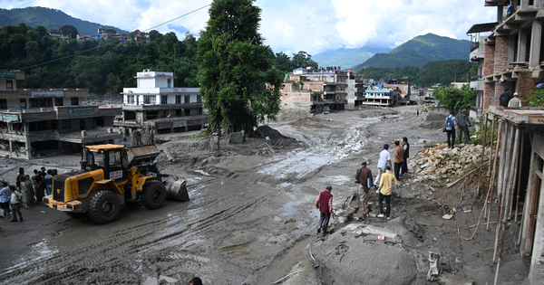 Workers use excavators to clear the mud following flash floods in Trishuli in Nepal's Nuwakot district on August 27, 2026.