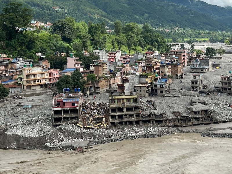 An aerial view shows a torrent of muddy water surging past houses and through the Trishuli River in the aftermath of flash floods at Trishuli Center in Nepal's Nuwakot district on September 1, 2026.