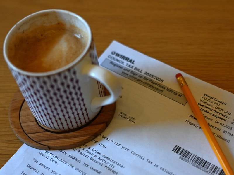 A council tax bill on a table next to a cup of coffee.
