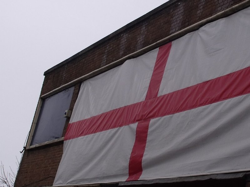 A large England flag hanging from the side of a building