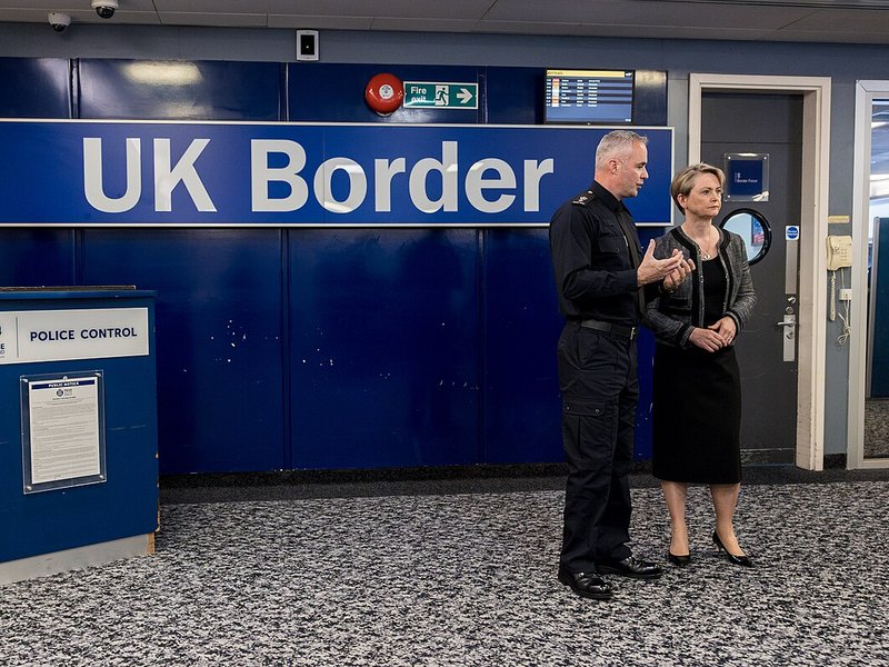 Home secretary Yvette Cooper standing beside a UK Border sign
