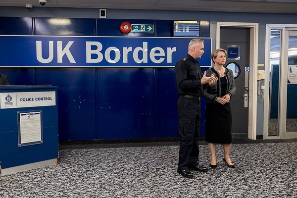 Home secretary Yvette Cooper standing beside a UK Border sign