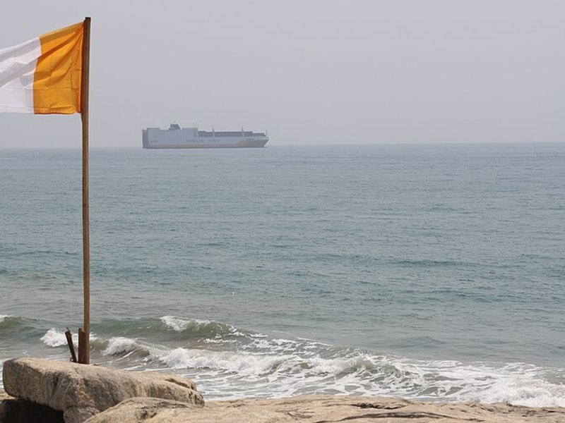 The Ivory Coast flag flies above some rocks by the sea