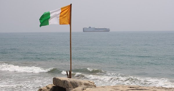 The Ivory Coast flag flies above some rocks by the sea