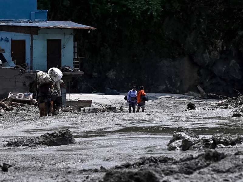 People carrying belongings through the aftermath of flash flooding in Nepal's Nuwakot district.