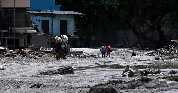 People carrying belongings through the aftermath of flash flooding in Nepal's Nuwakot district.