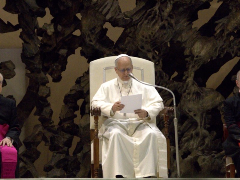 Pope Leo XIV delivering an address flanked by two cardinals