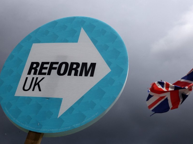 A placard with Reform UK’s logo on it with a Union Jack attached to a lamppost in the background.