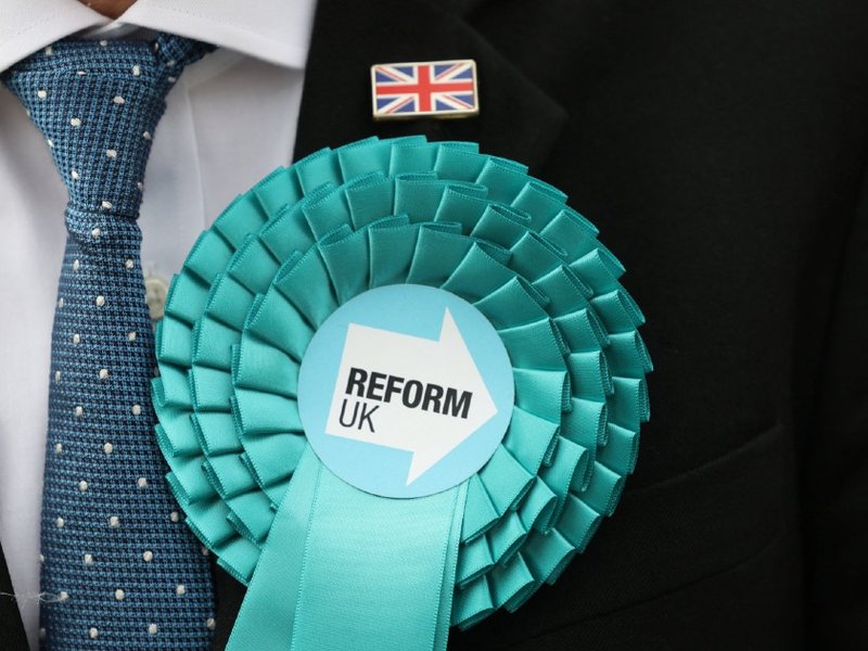 A person wearing a Reform UK rosette
