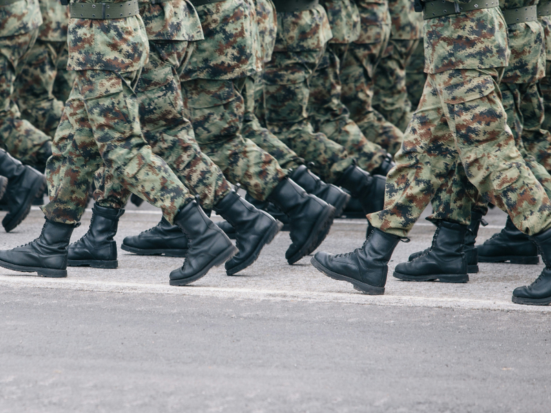 Soldiers dressed in army camouflage march in formation.
