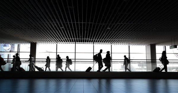 People with suitcases walking through a corridor in an airport