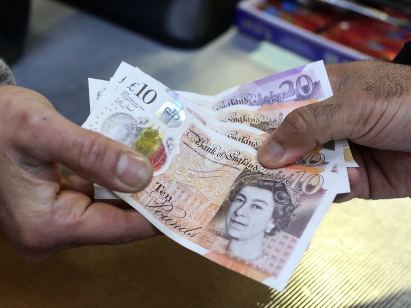 A person handing over some bank notes.