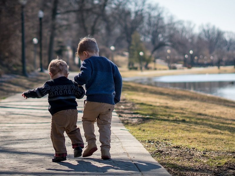 Two children walking by a pond