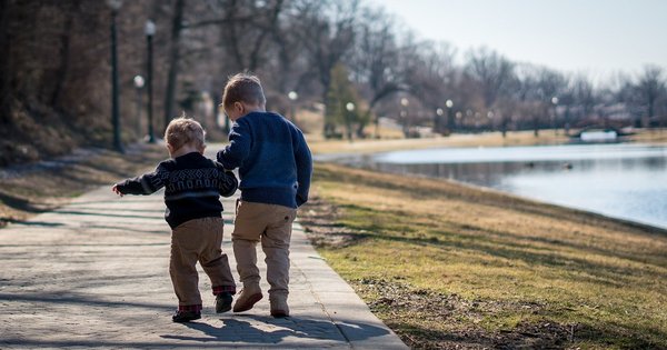 Two children walking by a pond