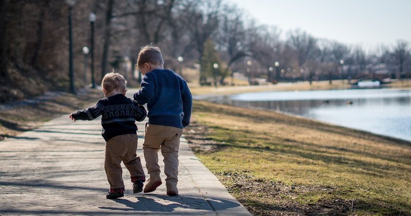 Two children walking by a pond