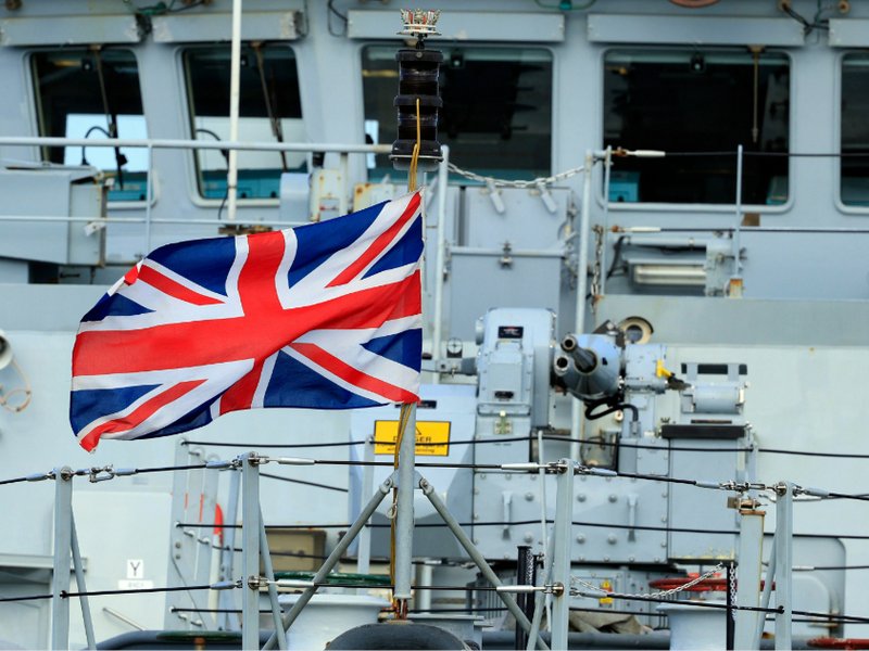 The Union Jack flying on the bow of the Royal Navy ship, HMS Tamar.