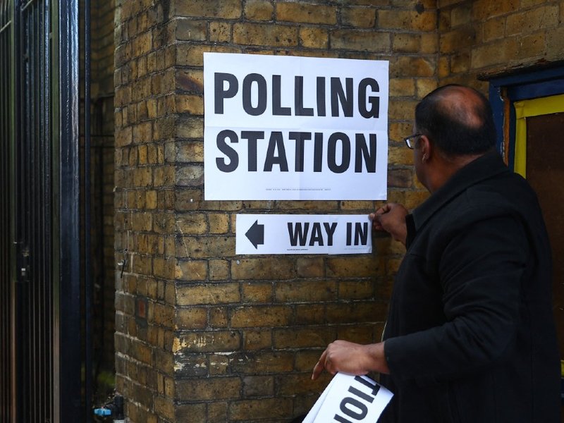 A person putting up a sign outside a polling station in London.